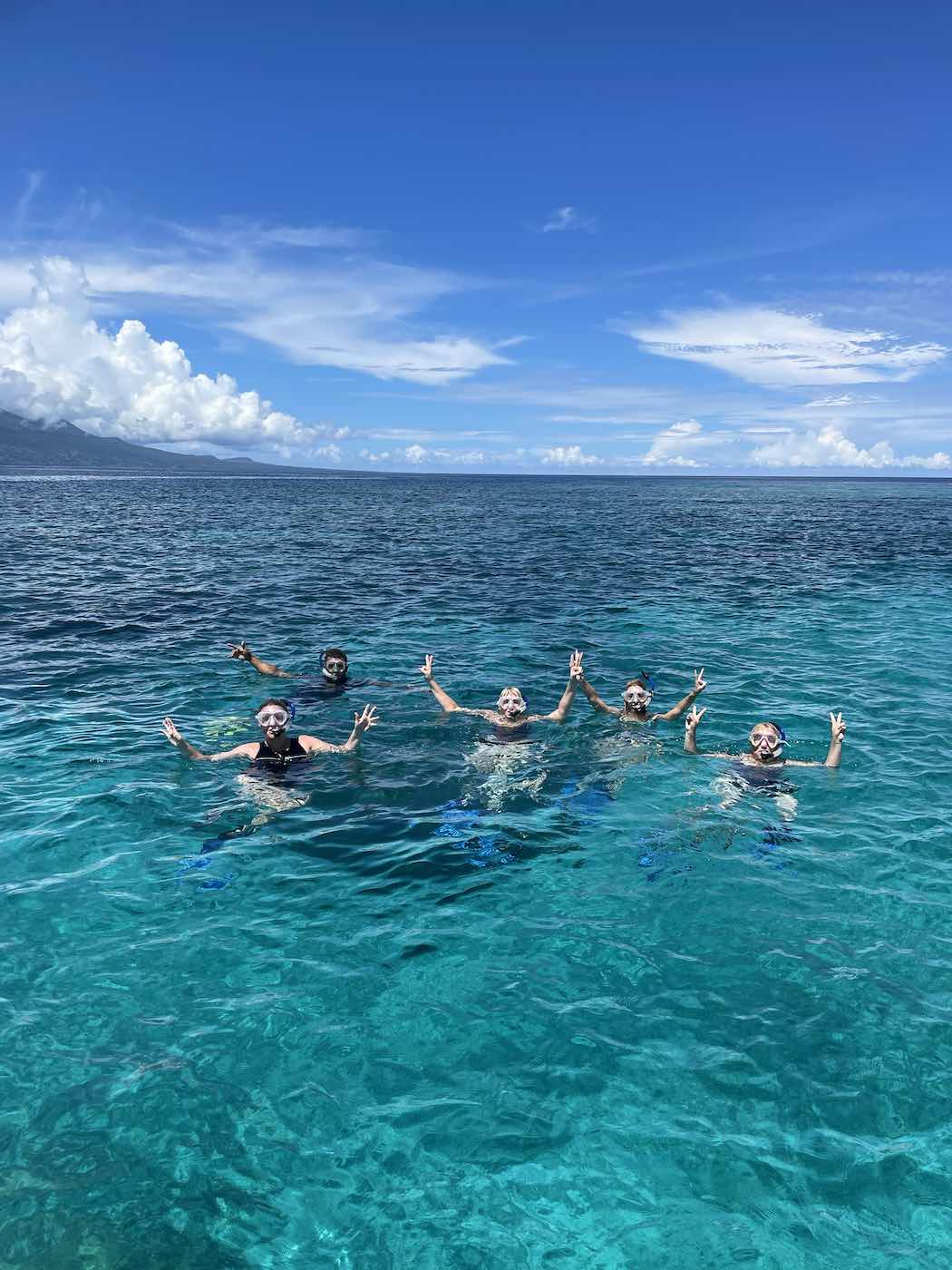 people snorkelling in the crystal clear blue water under blue skies